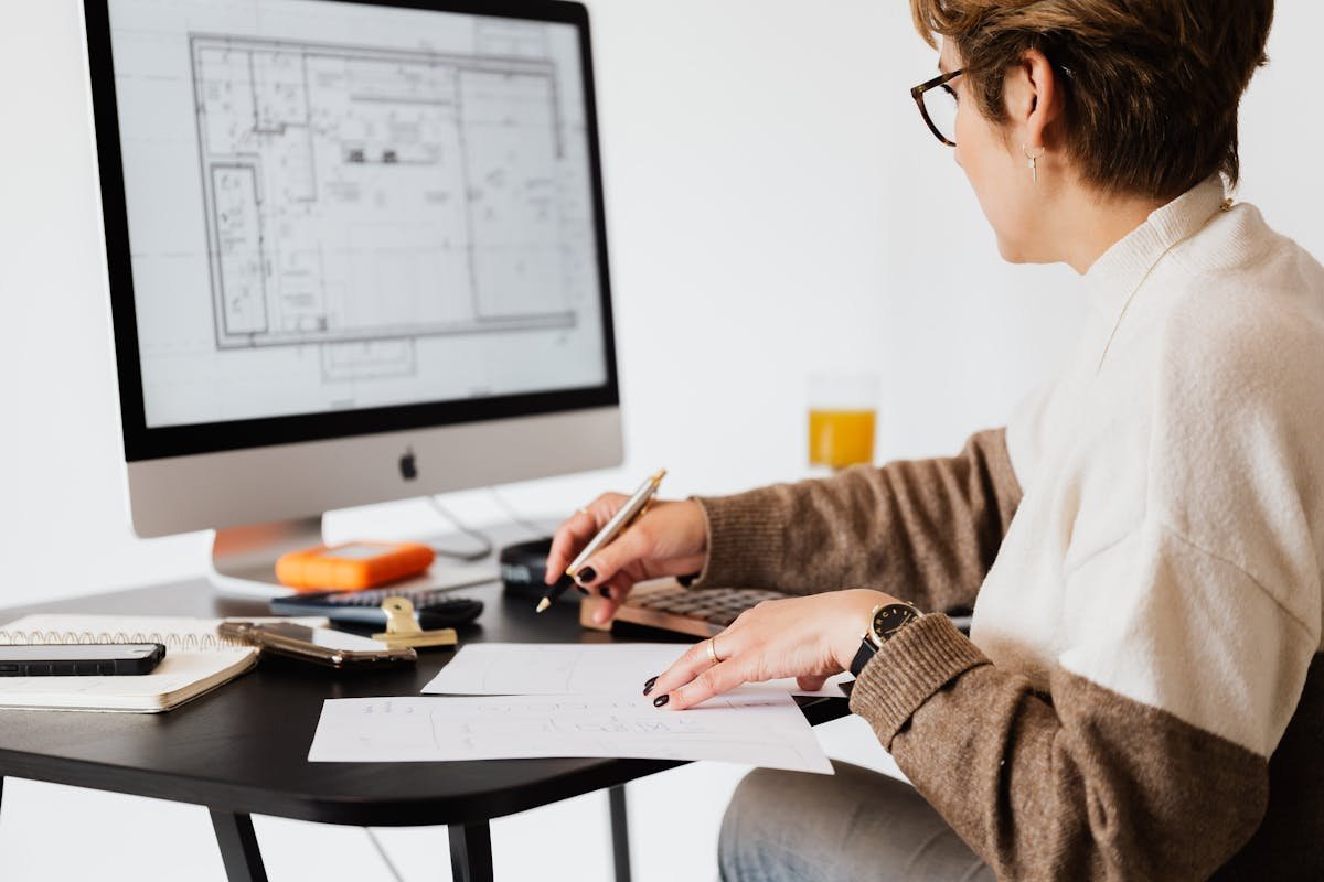 Commercial building surveyor reviewing architectural floor plans on a desktop computer in a professional UK office