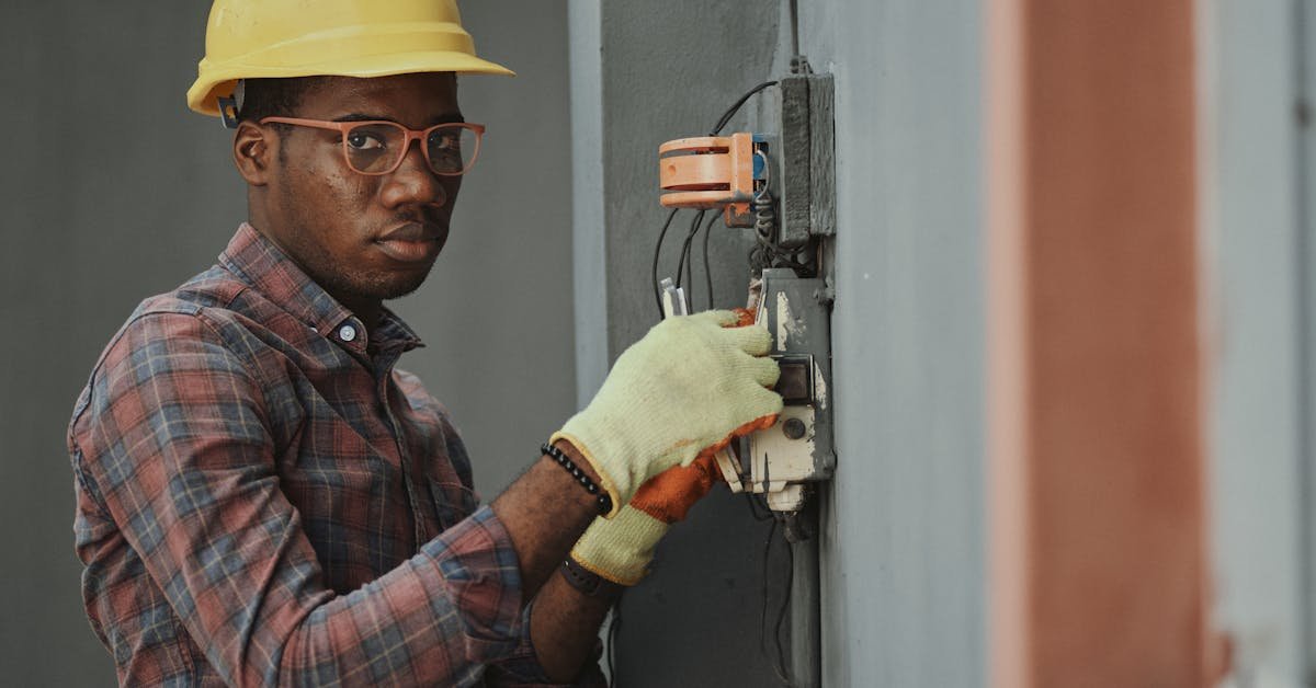 Safety inspector in hard hat and gloves examining an electrical panel — safety inspection relevant to asbestos management