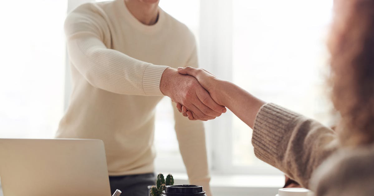 Two professionals shaking hands across a desk completing a commercial property purchase agreement
