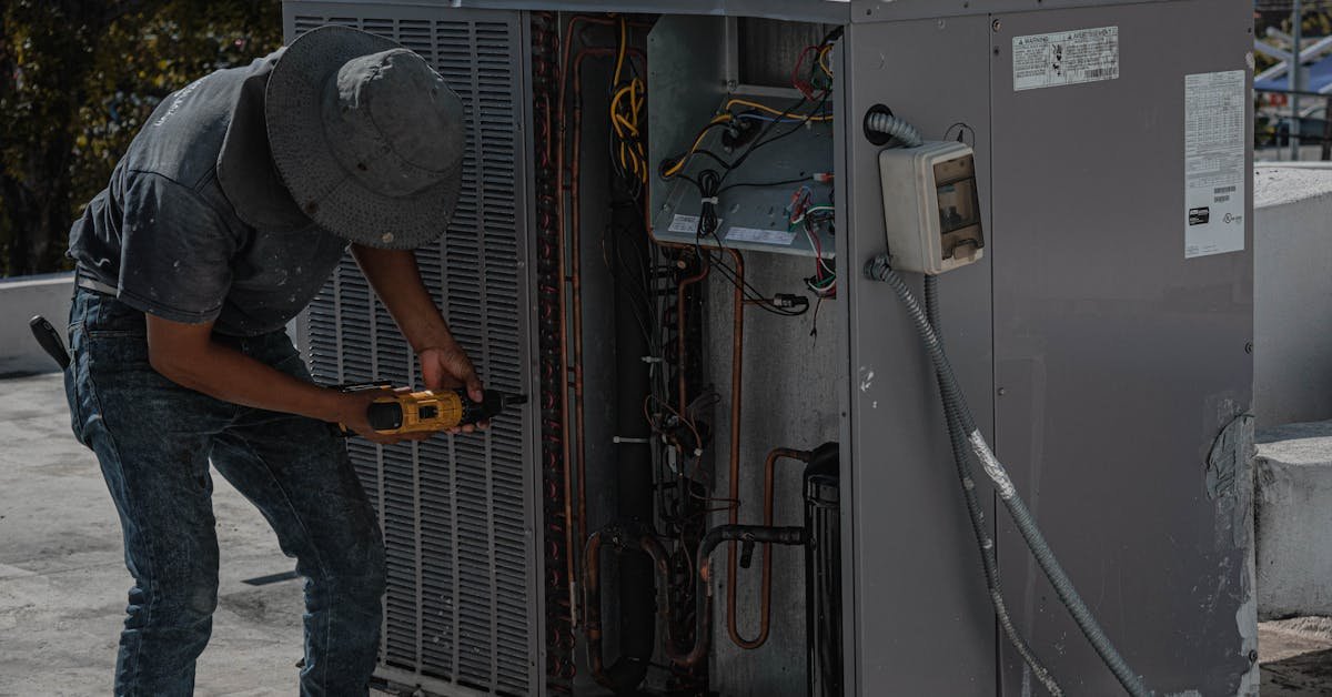 Maintenance worker servicing a commercial HVAC unit on a rooftop — building services and fire safety compliance