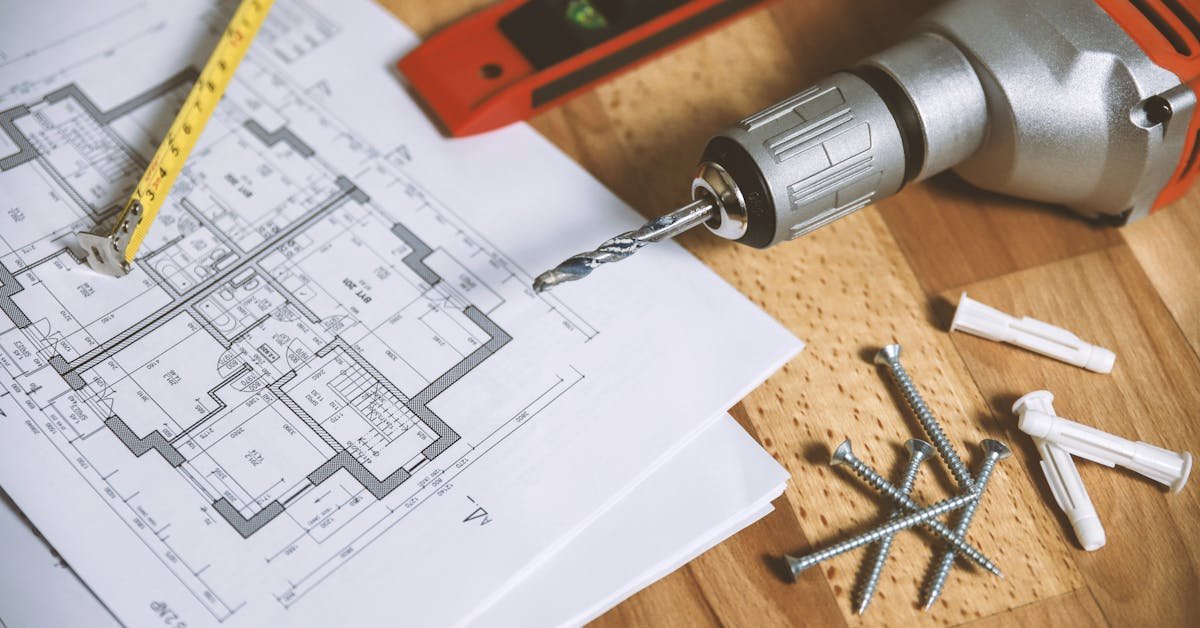 Floor plan drawings laid alongside a tape measure, spirit level and power drill ready for CAD production