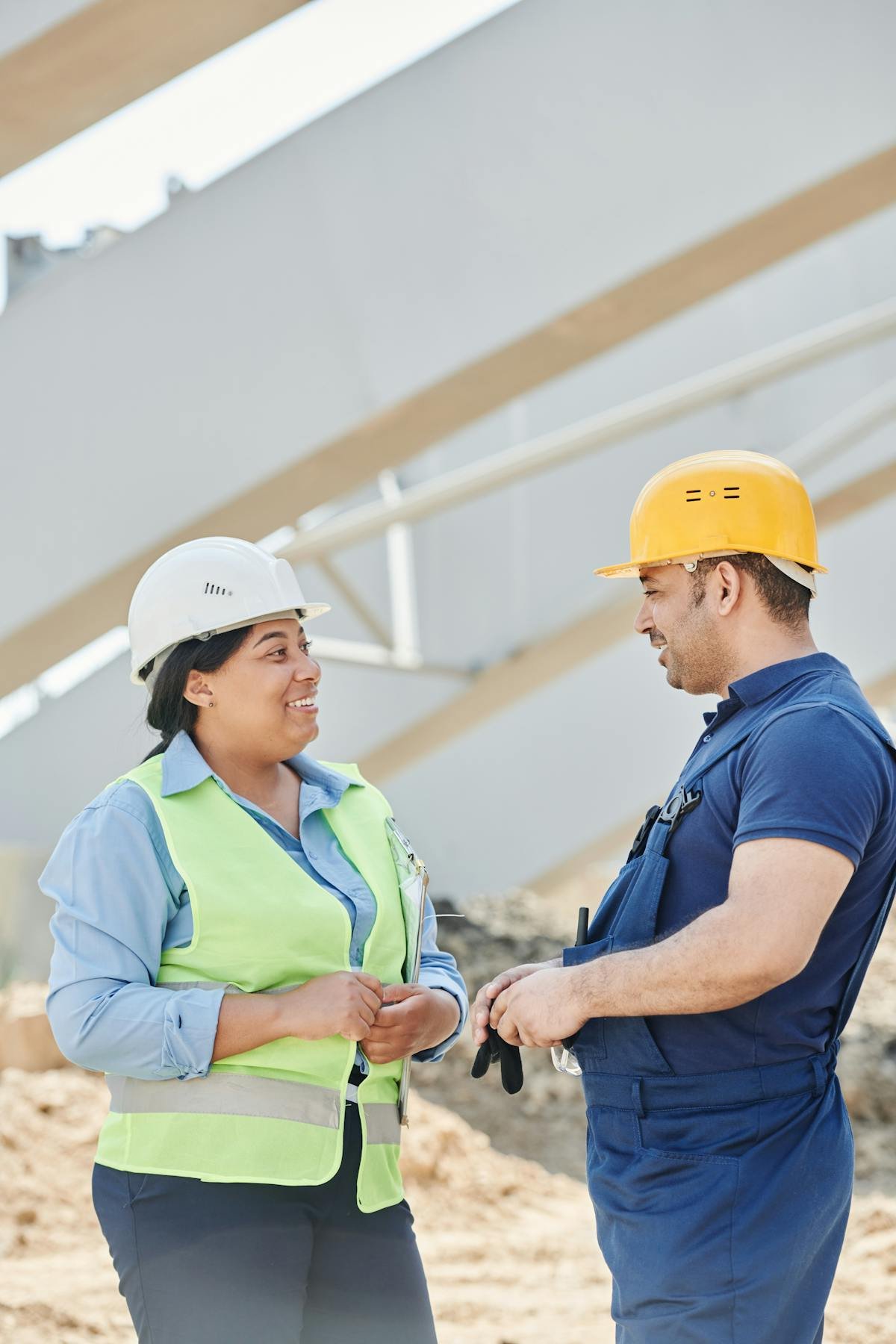 Two RICS-accredited commercial building surveyors on site at a UK commercial property, wearing hard hats and high-visibility vests