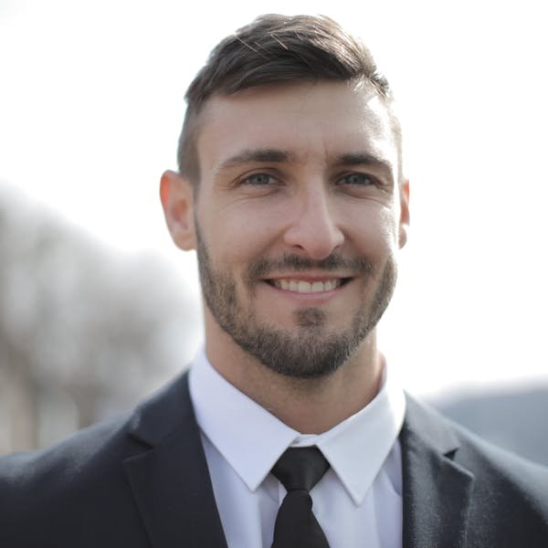 Marcus Patel, experienced Commercial Building Surveyor with silver hair, standing in a modern UK commercial building reception