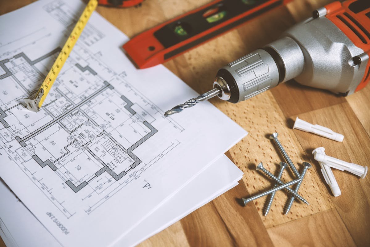 Commercial measured survey in progress — floor plan drawings laid out alongside a tape measure, spirit level and tools, ready for CAD production