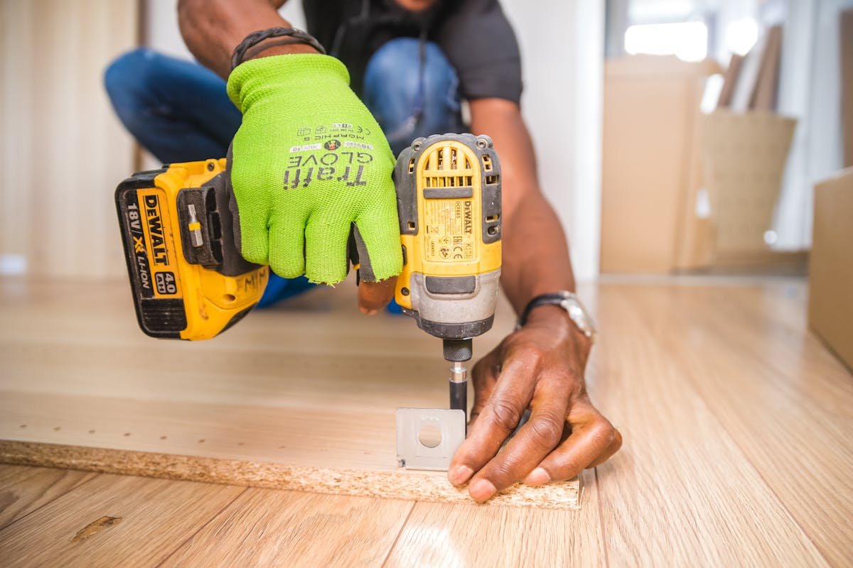 Maintenance engineer carrying out planned preventative maintenance work on a commercial building — using a cordless drill for repair and upkeep